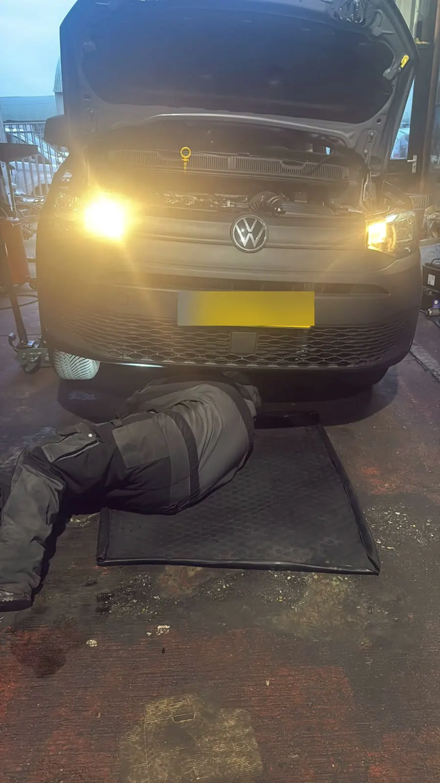 A mechanic under a van during an inspection