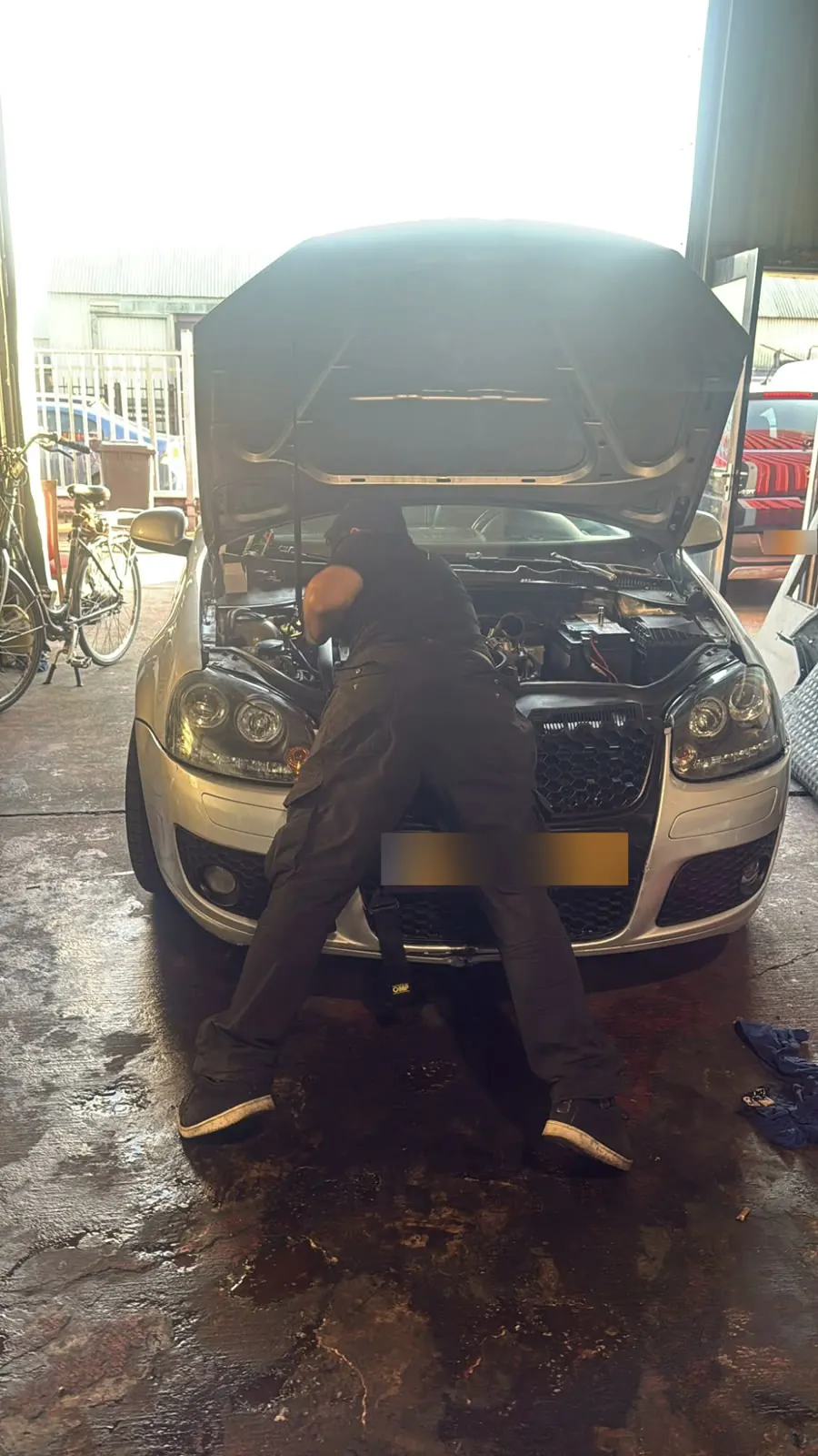 Een monteur werkt in de motorruimte van een Volkswagen Golf