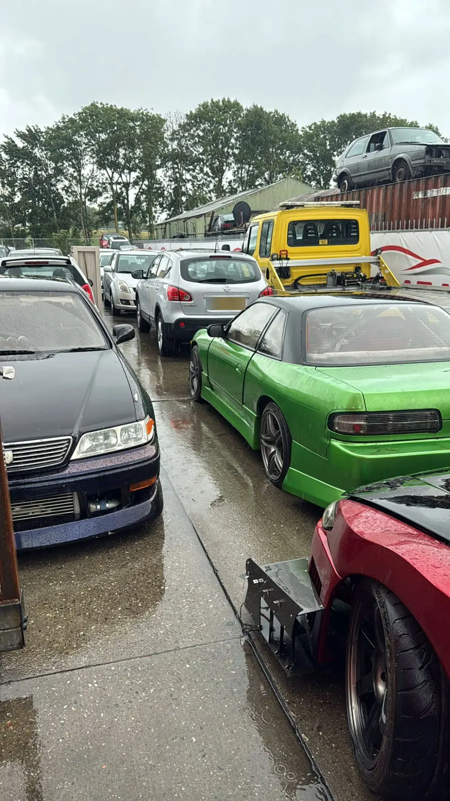 Carros estacionados no pátio de uma oficina em dia de chuva