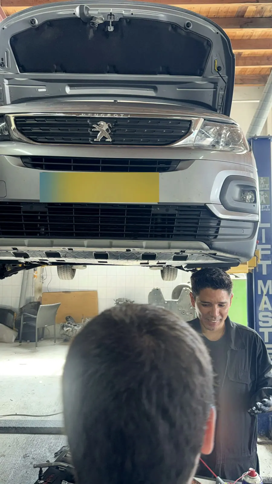 Luiz in gesprek met een klant onder een auto op de brug