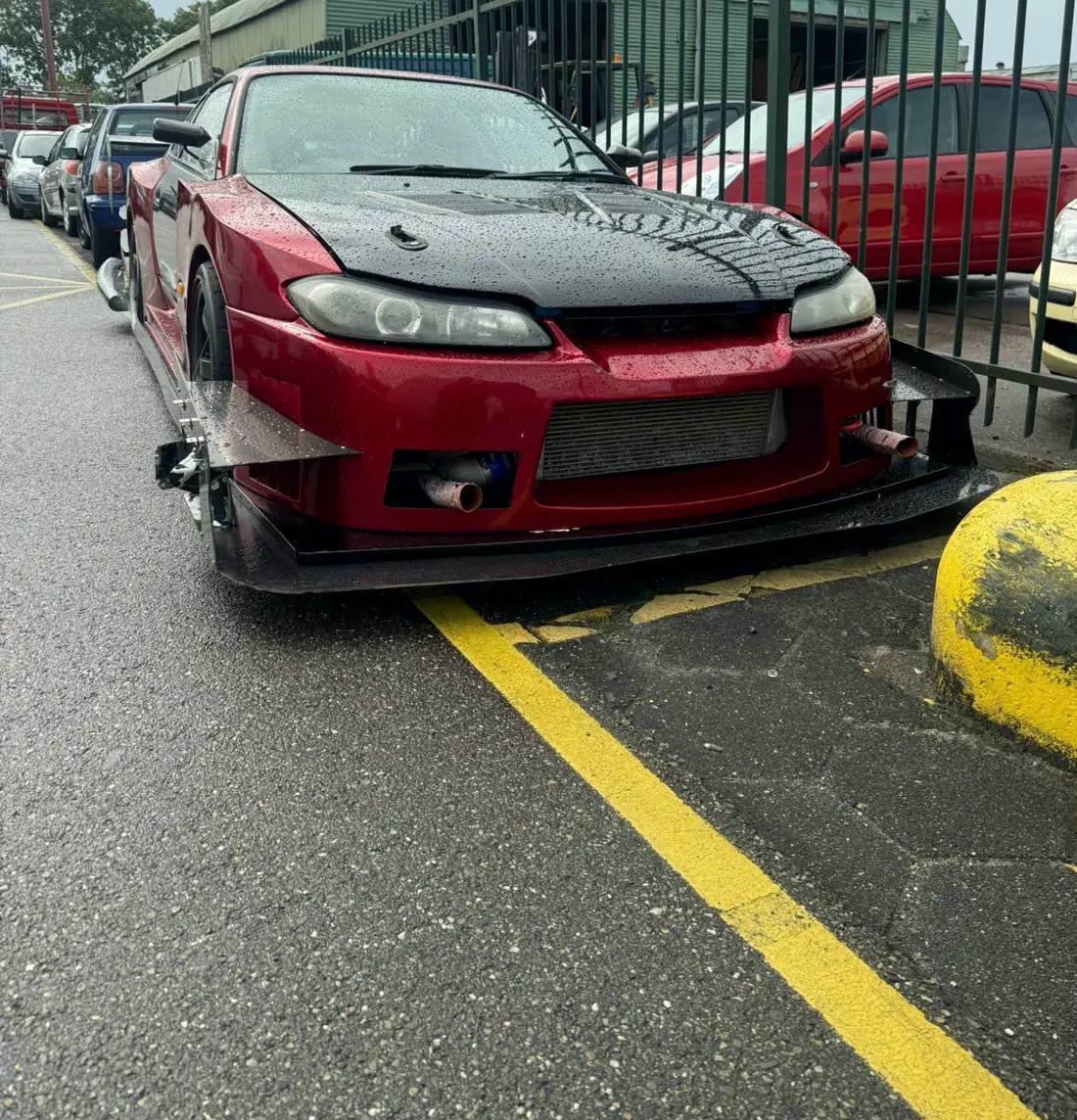 Carro vermelho estacionado com a pista molhada de chuva
