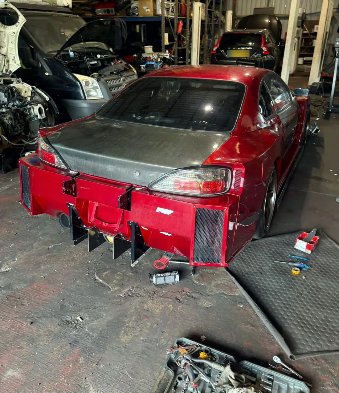 Achterkant van een rode Nissan Silvia S15 tijdens schadeherstel in de werkplaats